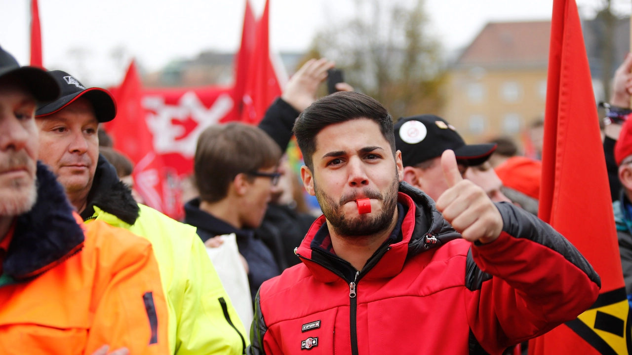 Ein junger Mann mit roter Jacke und Trillerpfeife streckt den Daumen nach oben.