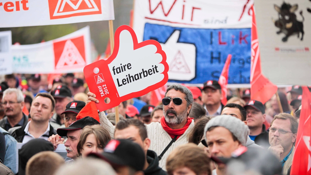 Ein Mann mit Sonnenbrille hält bei einer Demonstration ein Schild mit der Aufschrift: Faire Leiharbeit