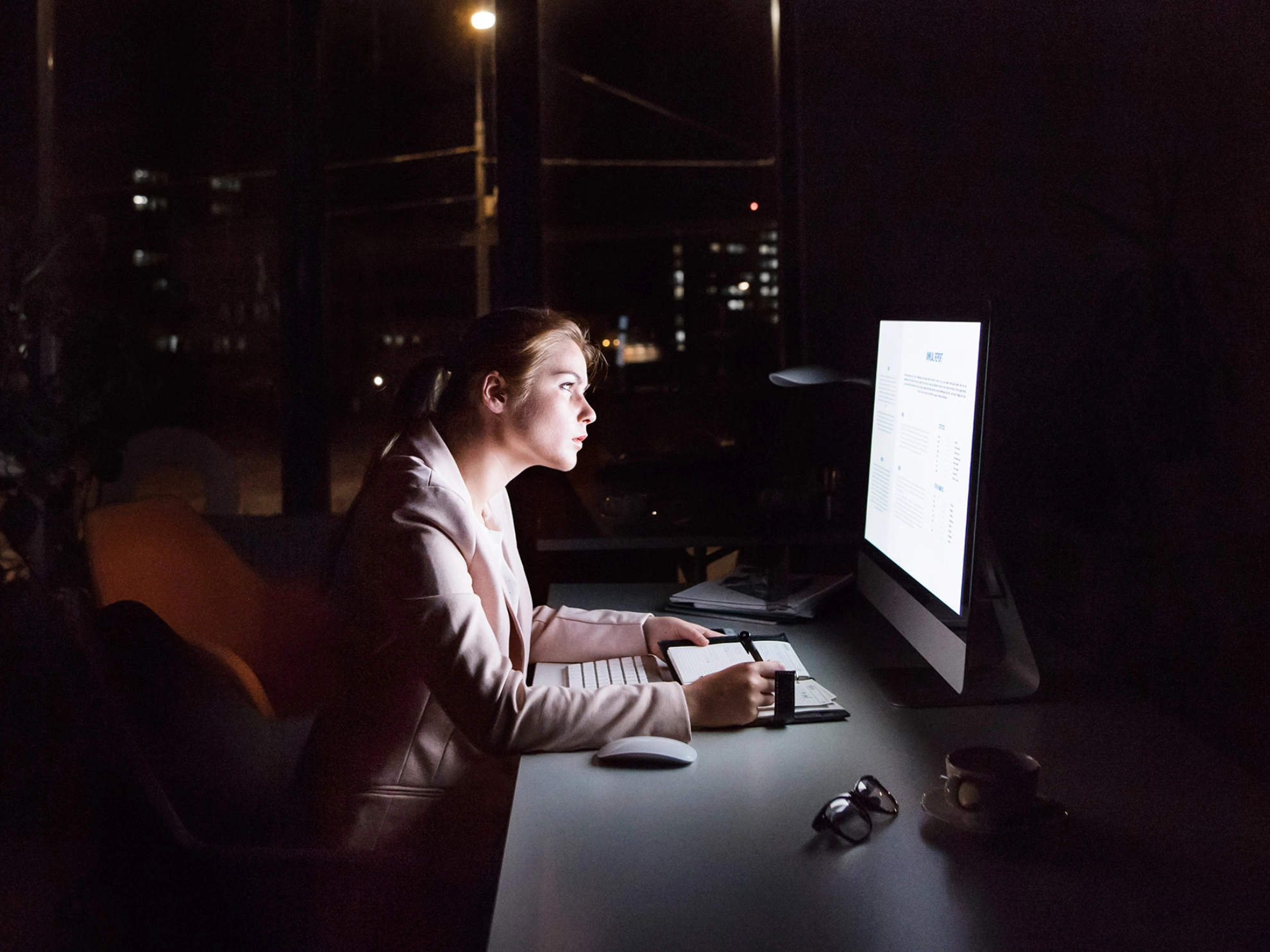 Geschäftsfrau vor Computer-Bildschirm im Büro in der Nacht