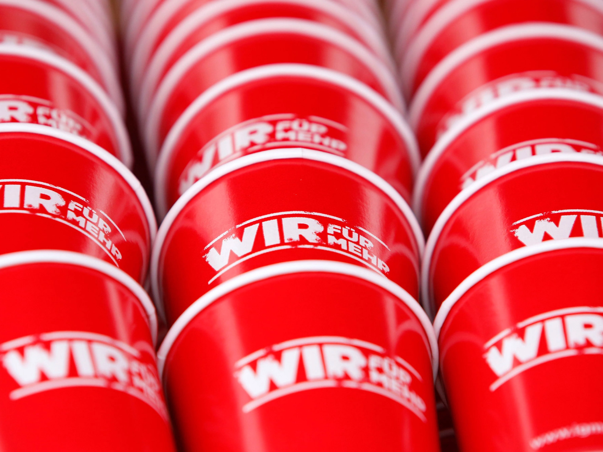 Rote Tassen mit 'WIR FÜR MEHR'-Druck.