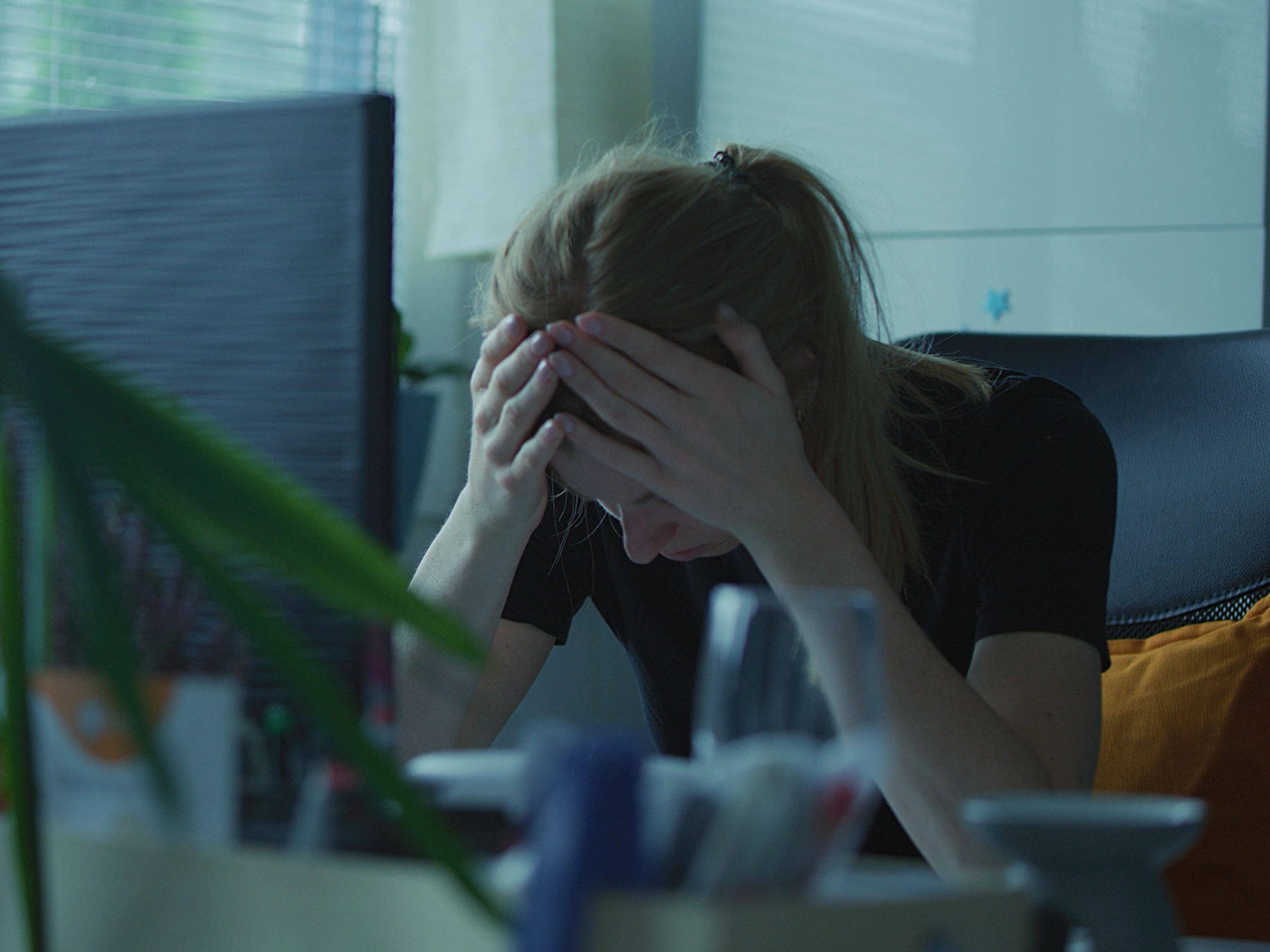 Frau mit gesenkten Kopf an ihrem Schreibtisch im Büro. 