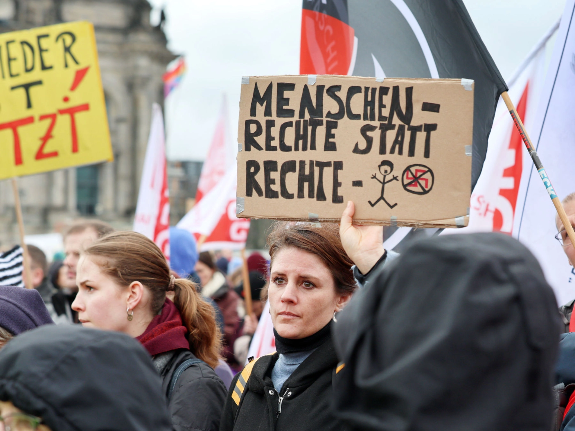 Menschenmenge bei einer Demo. Eine Frau hält ein Schild hoch mit der Aufschrift „Menschenrechte statt rechte Menschen“.