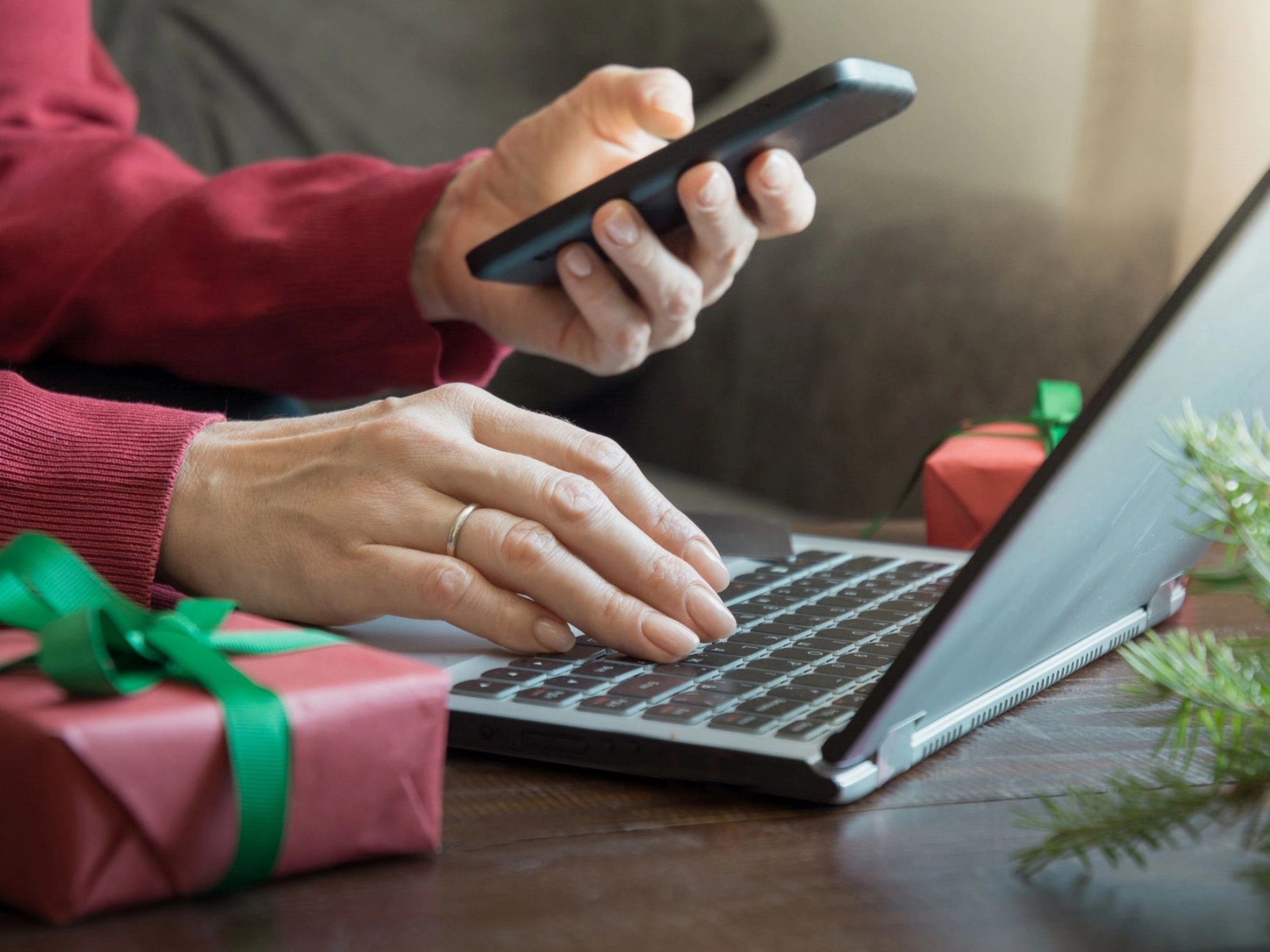 Beschäftigte:r mit Smartphone an einem Laptop