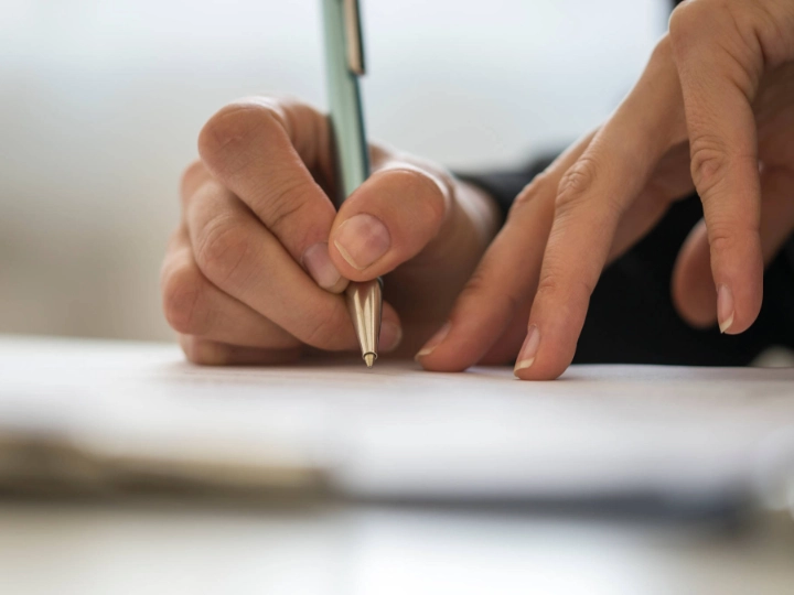 Jemand schreibt etwas auf ein Stück Papier.