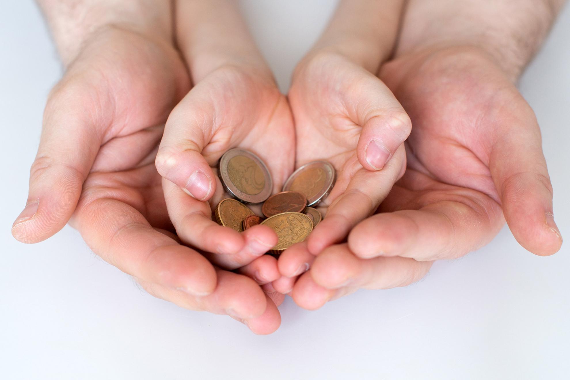 Vater und seiner Kind halten Euro-Münzen in den Händen